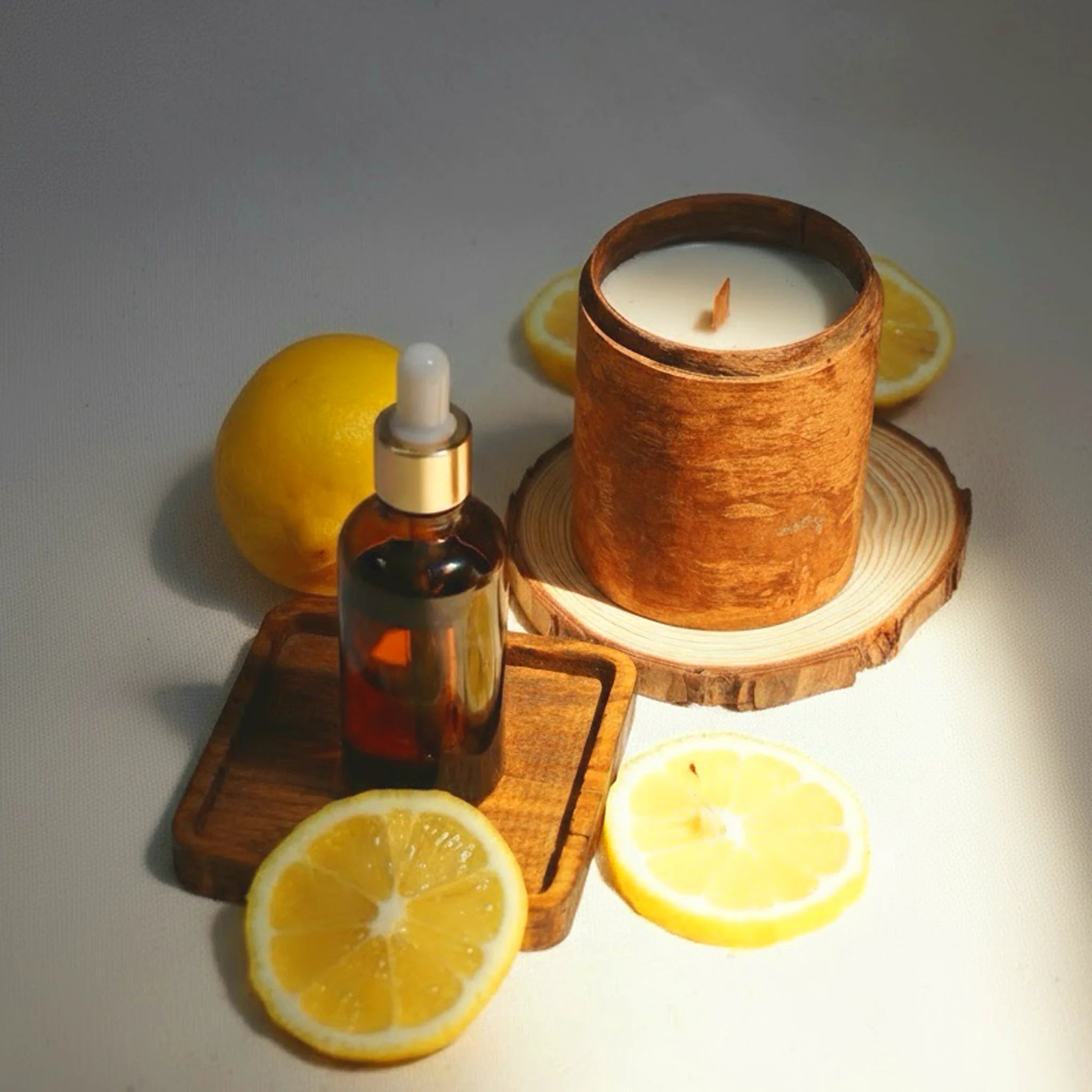 Endless Summer candle, essential oil with dropper, and lemons on a wooden surface