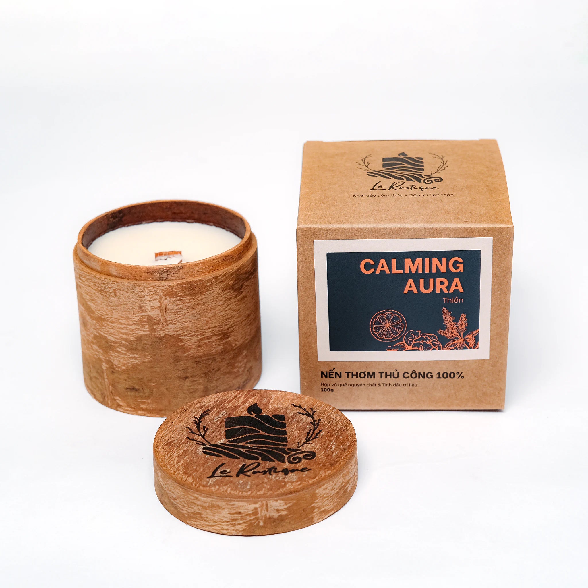 Candle in a wooden container with packaging labeled 'Calming Aura' on a white background