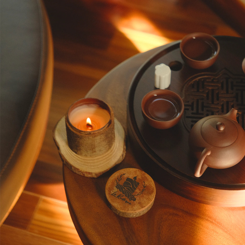 Tea set with teapot and cups on a wooden table with a natural soy wax candle for aroma fragrance.