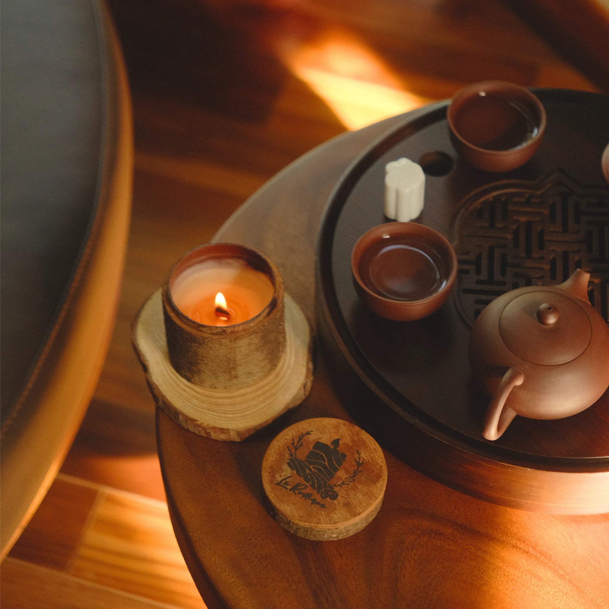 Tea set with teapot and cups on a wooden table with a natural soy wax candle for aroma fragrance.